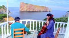 a photo of Reza and Fili performing in the Gaspe on a balcony overlooking the sea.