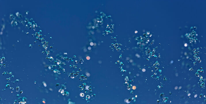 A blue image of particles. Strands of particles are arranged in an abstract, wavy manner.