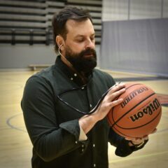 A photo of Dr. Jordan Zalis listening to a basketball with a stethoscope.