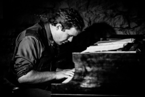 A black-and-white image of Matthew Endahl playing the piano.