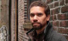 A portrait of Wayde Compton in front of a brick wall.