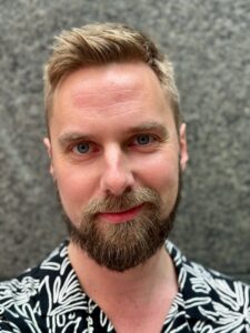 A close-up portrait of a person smiling at the camera.