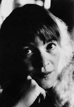 Black and white photo of Marilyn Crispell resting her face on her hand and looking into the camera.