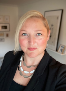 A photo of Dr. Sharon D. Engbrecht taken against a background of white walls with framed artwork, forming a corner behind them.
