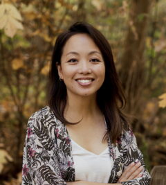 A head and shoulders portrait of Amy Hwang outdoors against a background of foliage.